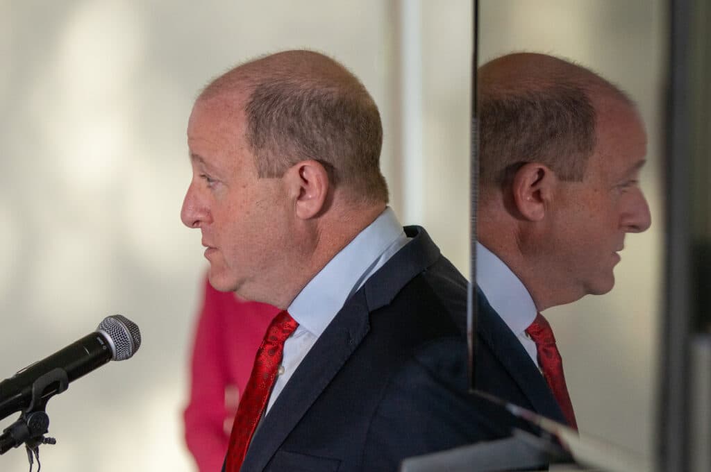 El gobernador de Colorado, Jared Polis, habla por un micrófono