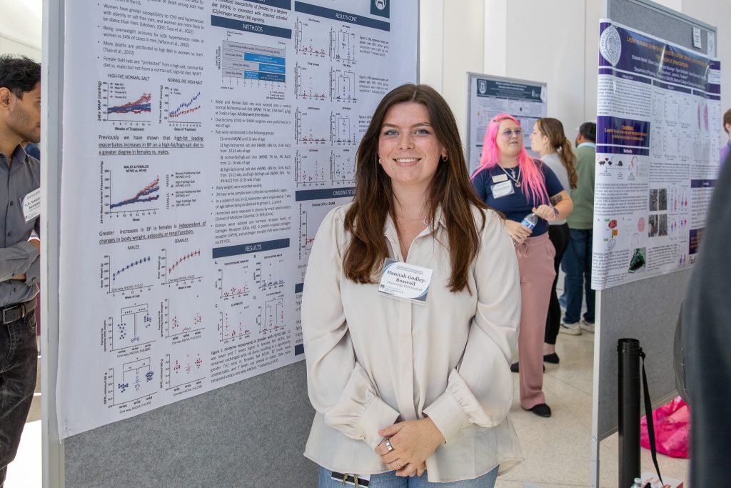 Una estudiante universitaria junto a un cartel de investigación científica durante un evento importante