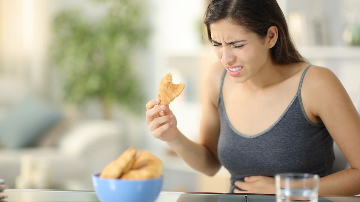 Mujer sosteniendo su estómago mientras come