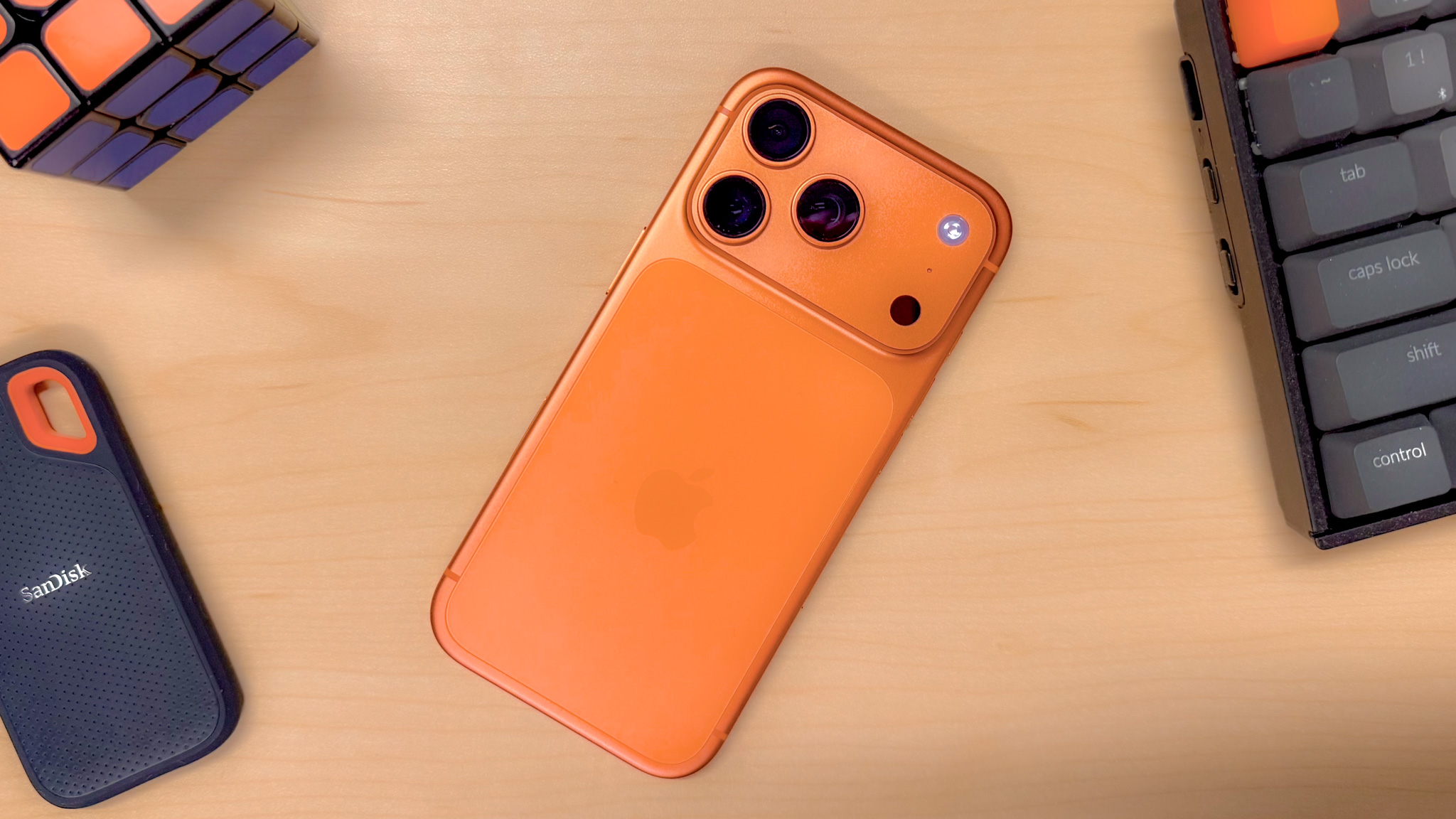 Un iPhone 17 Pro en Cosmic Orange, sobre un escritorio rodeado de objetos con detalles en naranja