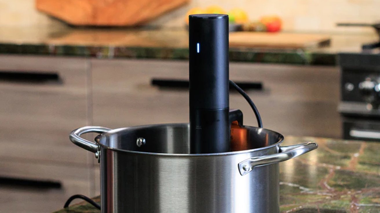 Circulador de inmersión sous vide en una olla grande de acero inoxidable sobre una encimera de cocina.