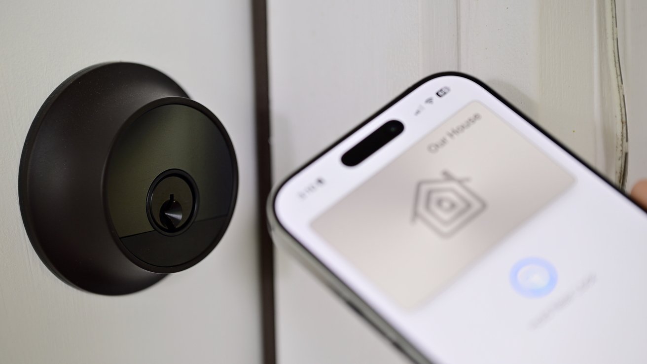 El teléfono inteligente está colocado cerca de una cerradura inteligente negra en una puerta y muestra una aplicación de control del hogar con un ícono y texto.