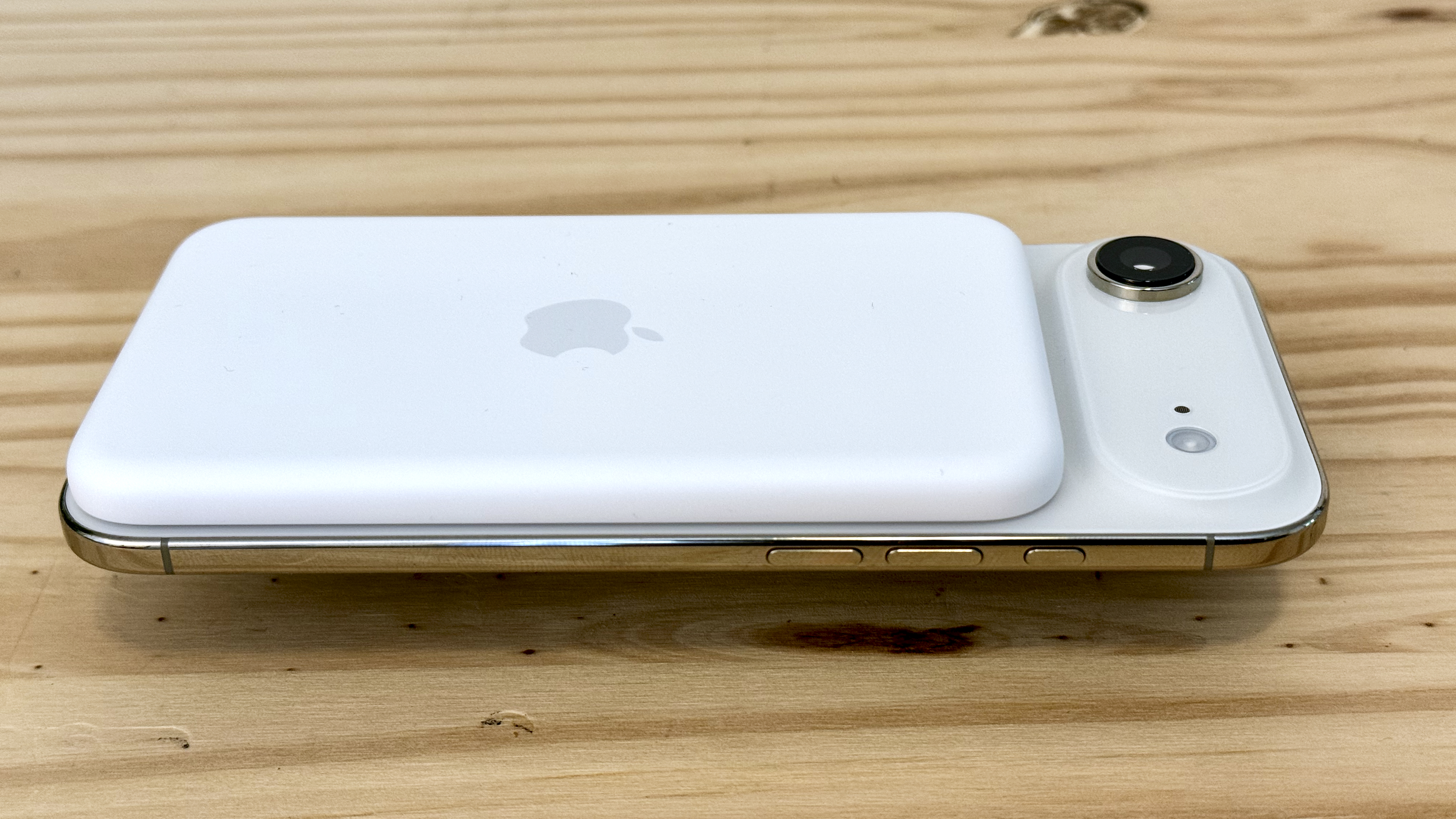 Batería MagSafe en iPhone Air, ligeramente elevada sobre una mesa de pino.
