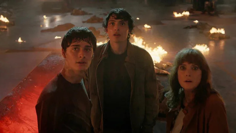 Will Byers de Noah Schnapp, Mike Wheeler de Finn Wolfhard y Joyce Byers de Winona Ryder están uno al lado del otro mirando Stranger Things.webp