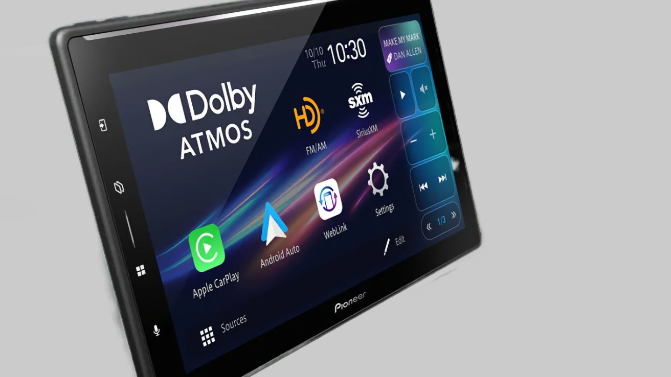 Pionero estéreo con pantalla táctil en el tablero que incluye Dolby Atmos, Radio, Apple CarPlay, Android Auto, WebLink y grandes botones azules de control multimedia en una interfaz oscura y colorida sobre un fondo gris.