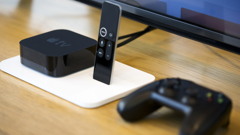 Apple TV 4K con mando a distancia y joystick sobre una mesa de madera