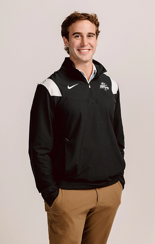 Braeden Shields '26 está de pie con una chaqueta Friars y las manos en los bolsillos.
