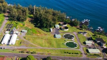 Vista aérea del Centro de Acuicultura con edificios, estanques, extensiones de césped y la costa de Hilo Bay.