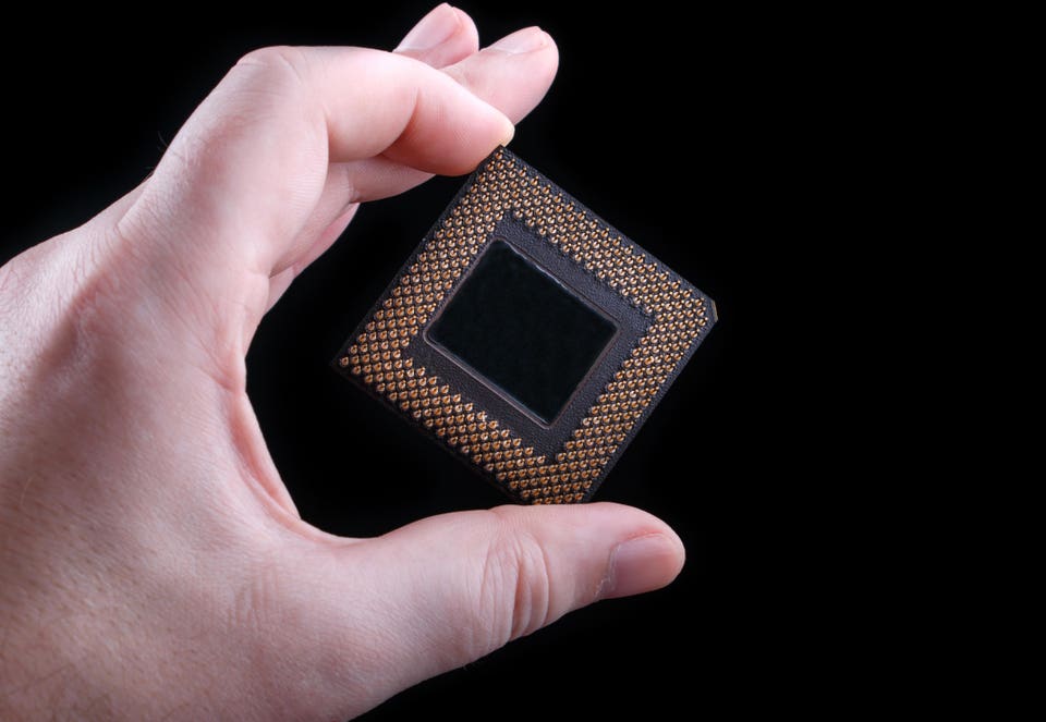 Mano masculina sosteniendo el procesador de la computadora sobre fondo negro
