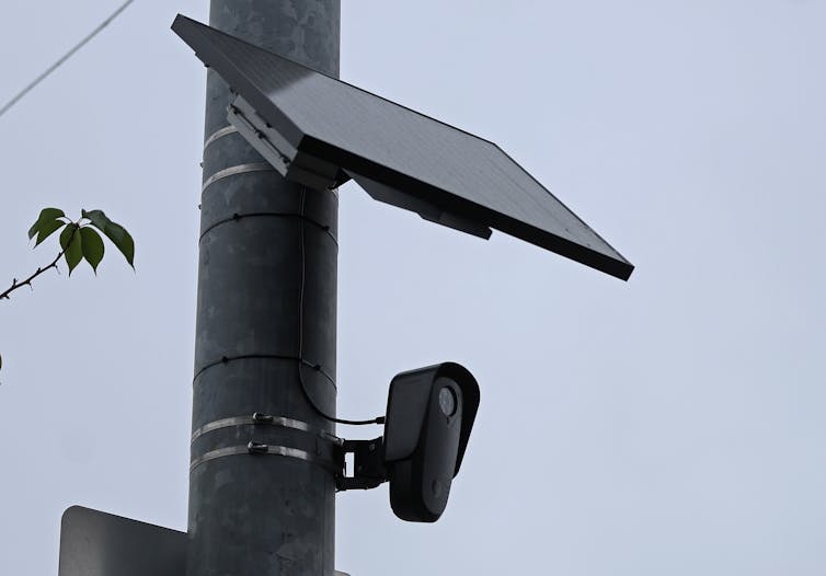 Una cámara y un panel solar están conectados a un poste de tráfico.