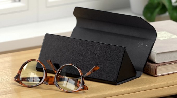 Una imagen de una mesa con un par de anteojos frente a un estuche de anteojos Satechi con Find My. Detrás de él, a la derecha, hay una pequeña pila de libros.